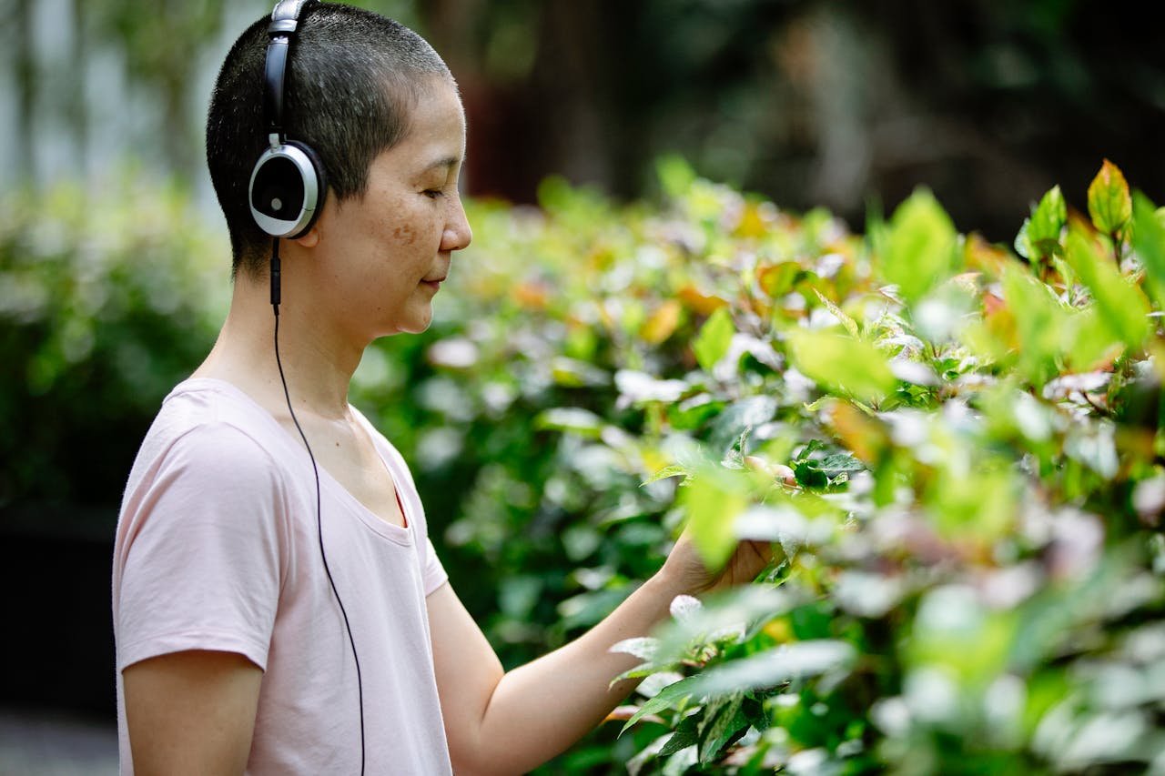 Asian woman listening to music in headphones in park